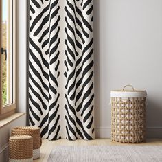 a zebra print curtain hanging on the side of a wall next to a basket and window