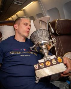 a man laying on an airplane holding a trophy