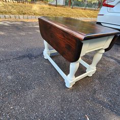 a white car parked next to a wooden table on top of asphalt covered parking lot