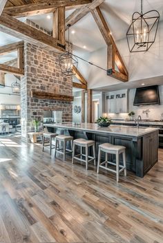 an open kitchen and living room with exposed beams in the ceiling, wood flooring and white cabinets