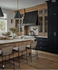 a large kitchen with wooden floors and black cabinetry on the walls, along with an island in the middle