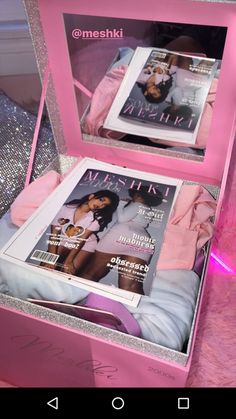 two magazines in a pink box on a bed