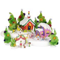 a christmas village with lots of trees and houses in the snow, including a rainbow colored house