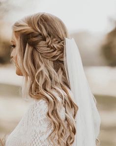 a woman with long hair wearing a wedding veil and braid in her hair, looking off to the side