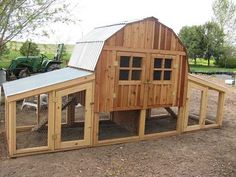 a large wooden chicken coop sitting in the middle of a dirt field next to a tractor