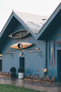 a blue building with two surfboards hanging from it's roof and bikes parked in front