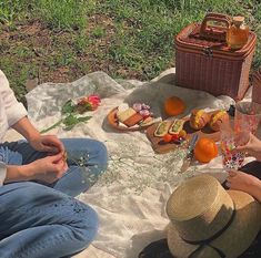 two women sitting on the ground with food and drinks