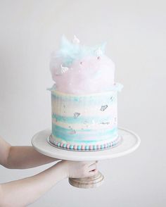 a woman holding a cake on top of a white plate in front of a tweet