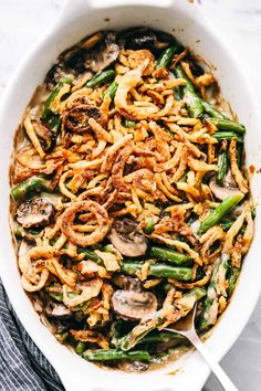 green bean casserole with mushrooms and onions in a white dish on a blue towel