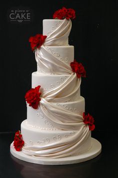 a three tiered white wedding cake with red flowers