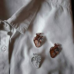 three heart shaped pins sitting on top of a white shirt