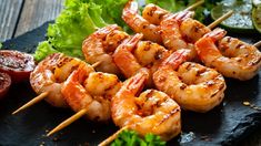 shrimp skewers with lettuce and ketchup on a black plate