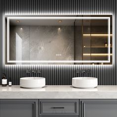 a bathroom vanity with two sinks and a large mirror above it that lights up the room