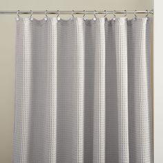 a white shower curtain hanging from a metal rod