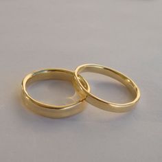 two gold wedding rings sitting on top of each other