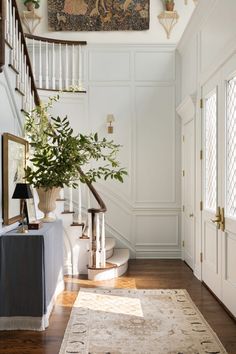 a large painting hanging on the wall above a stair case in a white room with wood floors