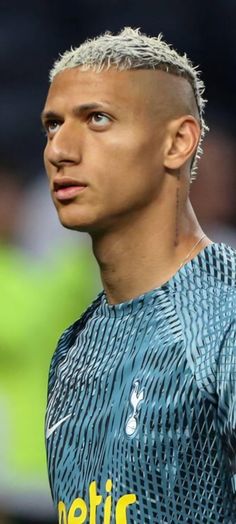 a soccer player with short hair and piercings on his head looking off to the side