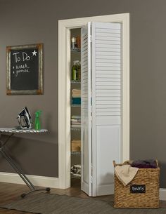 an open pantry door in a room with a chalkboard on the wall behind it