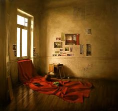 an empty room with a red blanket on the floor and several pictures hanging on the wall