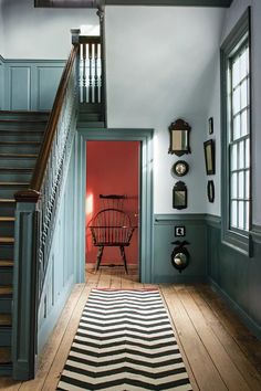 the hallway is painted blue and has a striped rug on the floor next to it