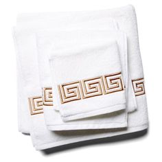 three white towels with gold greek designs on them, one is folded and the other two are folded