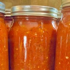 three jars filled with red sauce sitting on top of a counter