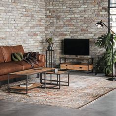 a living room with brick walls and a brown leather couch in front of a flat screen tv