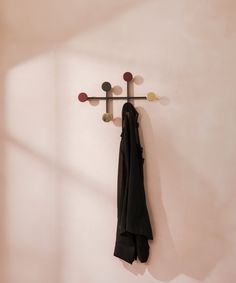 a coat rack with two coats hanging from it's hooks and a scarf on the wall