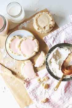 some cookies are on a table with pink icing and powdered sugar in them