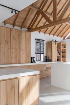 an open kitchen with wooden cabinets and white counter tops, along with wood beams on the ceiling