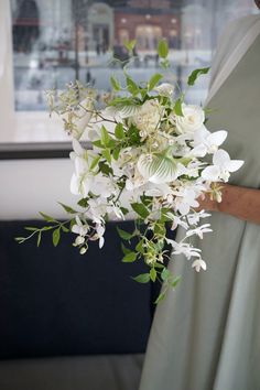 a woman holding a bouquet of white flowers in her hand and wearing a green dress