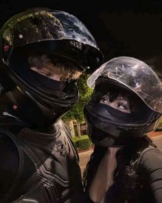 two people wearing helmets are standing next to each other