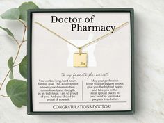 a gold necklace with the words, doctor of pharmacy on it in front of a box