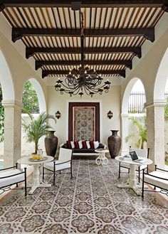 a living room filled with furniture and a chandelier hanging from the ceiling above