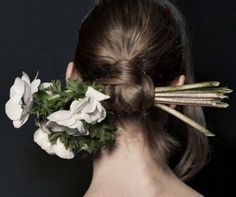 a woman with flowers in her hair is seen from the back, looking at something