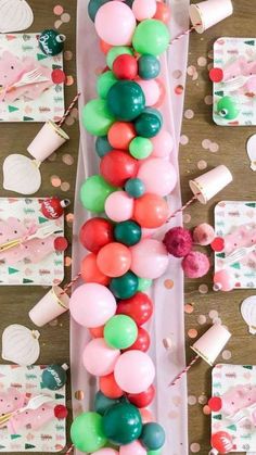 some balloons and confetti on a table with pink, green and red decorations