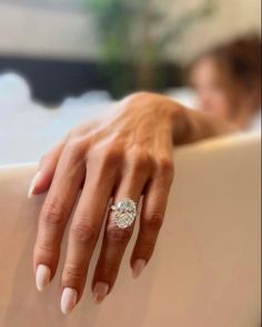 a close up of a person's hand with a diamond ring on their finger