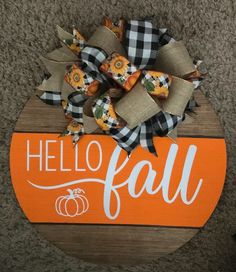 an orange and black sign with the word hello fall on it, sitting on carpet