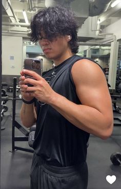 a man taking a selfie with his cell phone in a gym room while wearing sweatpants