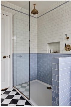 a bathroom with blue and white tiles on the floor, shower stall and sink area