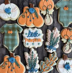 some decorated cookies are sitting on a wooden table with the words little pumpkin written on them