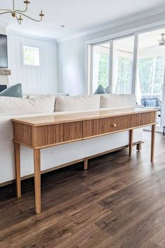 a living room with hardwood floors and white couches in front of large windows that look out onto the water