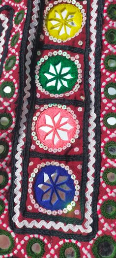 a colorful piece of cloth with different colored circles and flowers on the side, along with buttons