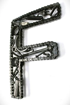 the letter f is made out of chains and other metal parts on a white surface