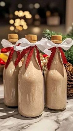 three bottles filled with brown liquid sitting on top of a table next to pine cones