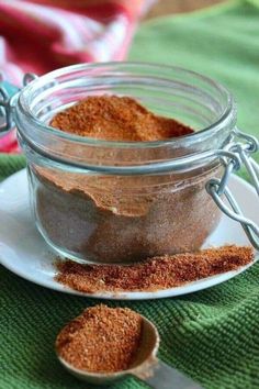 homemade chili seasoning mix in a glass jar on a white plate next to a spoon