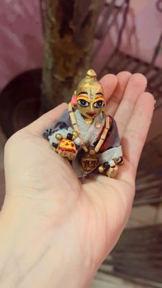 a hand holding a small figurine in it's palm