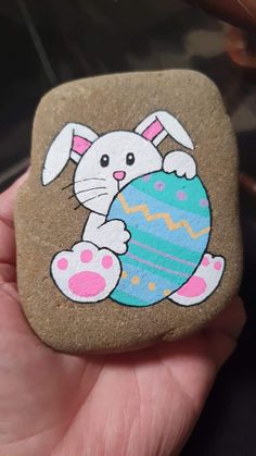 a hand holding a rock with an easter bunny painted on it