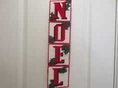 a cross stitch door hanger with the word noel spelled in red and green letters