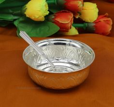 a bowl with two spoons in it sitting on a table next to tulips